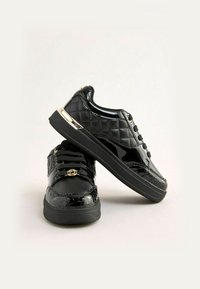 Mustad nahast madala profiiliga tossud, millel on tikand ja kuldsed aktsendid kanna ja paelte peal.