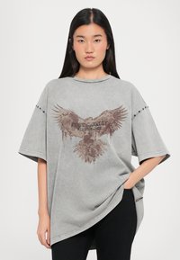 Oversized grijze t-shirt met een bruine arendafbeelding en de tekst "JUST CAVALLI", korte mouwen en een ronde zoom.