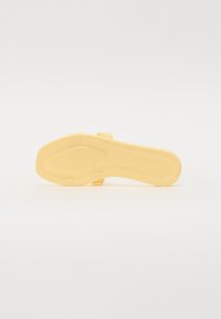 Gul sandal sula med en texturerad yta med ribbor, en oval utskärning och cirkulära accenter för grepp. Slät plastmaterial.