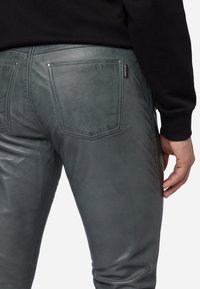 Grijze nep leren broek met een gladde textuur, een getailleerde pasvorm en twee achterzakken, met zichtbare stiksels en een merketiket.