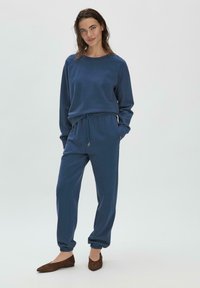 Sudadera de color azul marino rica en algodón y pantalones de chándal a juego con puños elásticos y cordón. Diseño simple con cuello acanalado y bolsillos laterales.