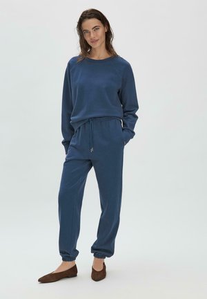Felpa blu navy in cotone con pantaloni coordinati, dotati di polsini elastici e cordino. Design semplice con scollatura ribattuta e tasche laterali.
