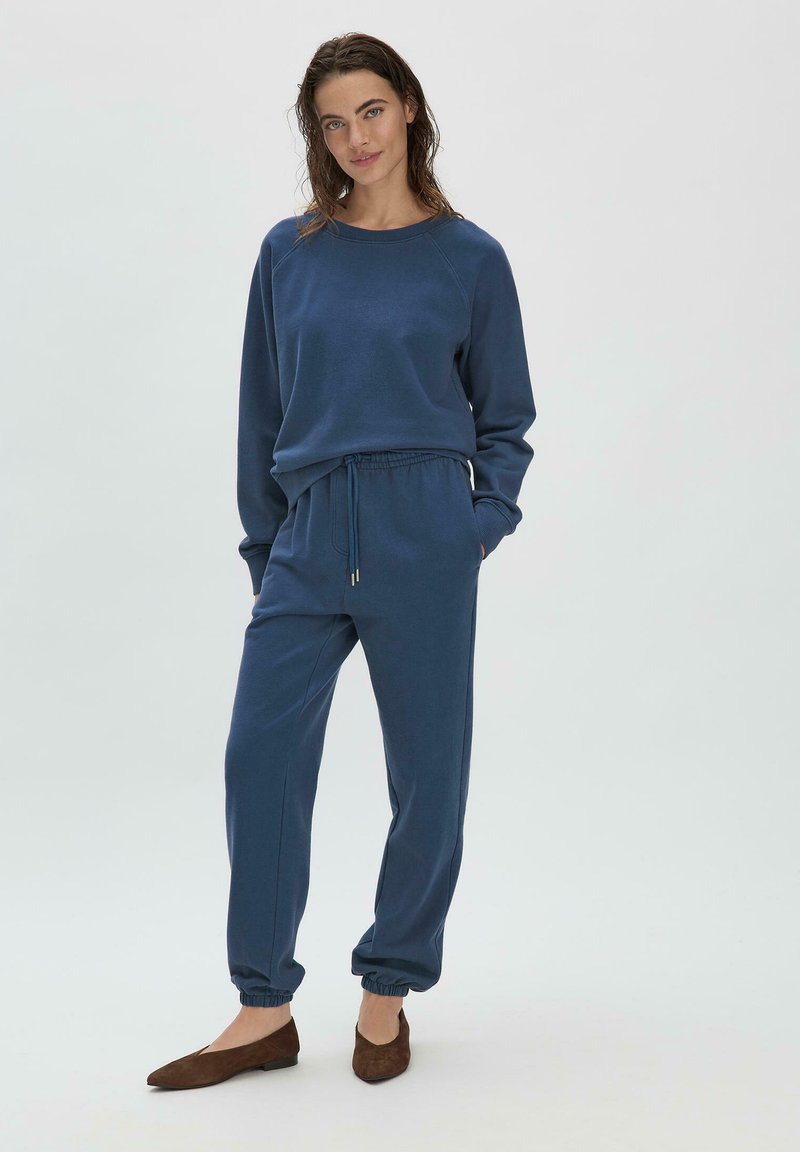 Sudadera de color azul marino rica en algodón y pantalones de chándal a juego con puños elásticos y cordón. Diseño simple con cuello acanalado y bolsillos laterales.