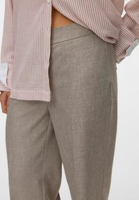 Lichtbruine, gestructureerde broek met een rechte snit. Met zijzakken en een platte tailleband, gecombineerd met een gestreept shirt.