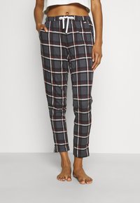 Checked pajama pants in dark gray with red and white lines, featuring an elastic waistband and side pockets. Cotton material, cropped length.