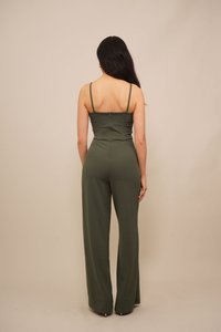 Une combinaison olive avec des bretelles spaghetti, un corsage ajusté, un design à jambes larges et une fermeture éclair dans le dos. Texture lisse et accents minimalistes.