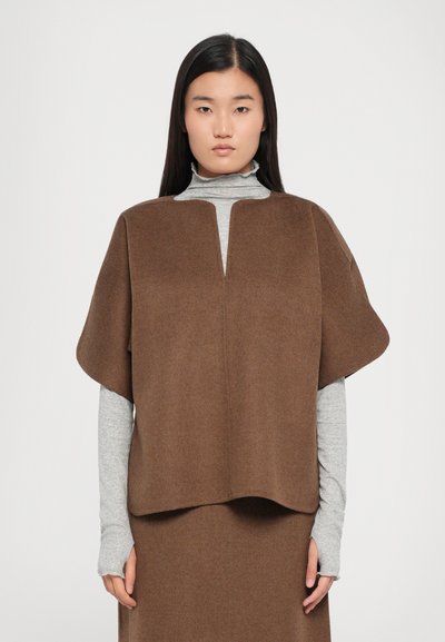 Top de mezcla de lana marrón con un diseño amplio y tipo capa, con un profundo escote en V. Usado sobre un jersey de cuello alto en gris claro de manga larga. Textura suave.