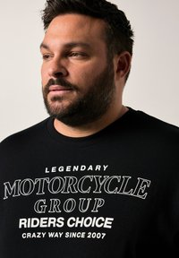 Černá mikina s výrazným bílým textem: "Legendární motocyklová skupina Výběr jezdců Šílený způsob od roku 2007." Design s kulatým výstřihem.