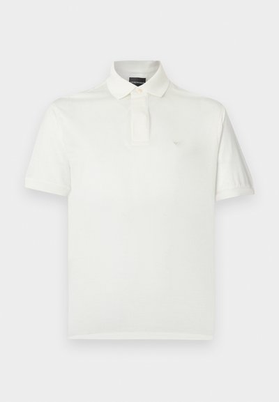 Bílé polo tričko z měkké bavlny s klasickým límečkem, krátkými rukávy a malým logem na hrudi. Hladká textura.