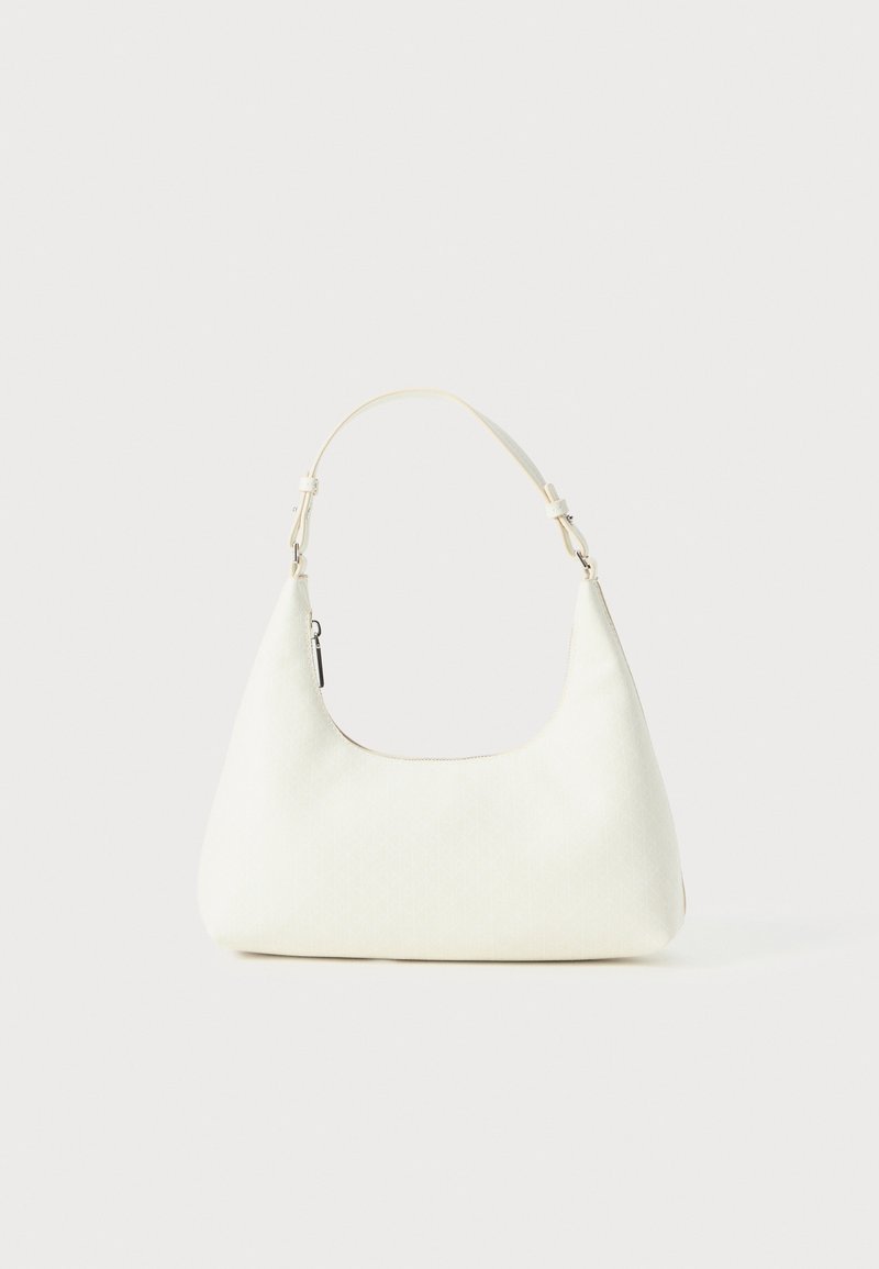 Μικρή λευκή τσάντα ώμου με μία ρυθμιζόμενη λουρί και κλείσιμο με φερμουάρ, τοποθετημένη σε απλή λευκή φόντο.