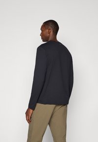 Zwarte lange mouwen T-shirt van zacht katoen met een ronde hals, voorzien van een minimalistisch ontwerp zonder zichtbare logo's of patronen.