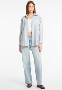 Gestreept, lichtblauw shirt van katoen. Het heeft lange mouwen, een knoopsluiting aan de voorkant en een ontspannen pasvorm. Gecombineerd met licht gewassen jeans.