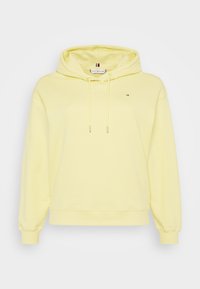 Jasnożółta bluza z kapturem, z trokami, małym logo Tommy Hilfiger na piersi oraz prążkowanymi mankietami i dołem.