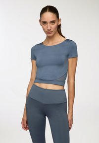 Top corto atletico blu con maniche corte, design senza cuciture e dettagli testurizzati, abbinato a leggings high-waisted coordinati.