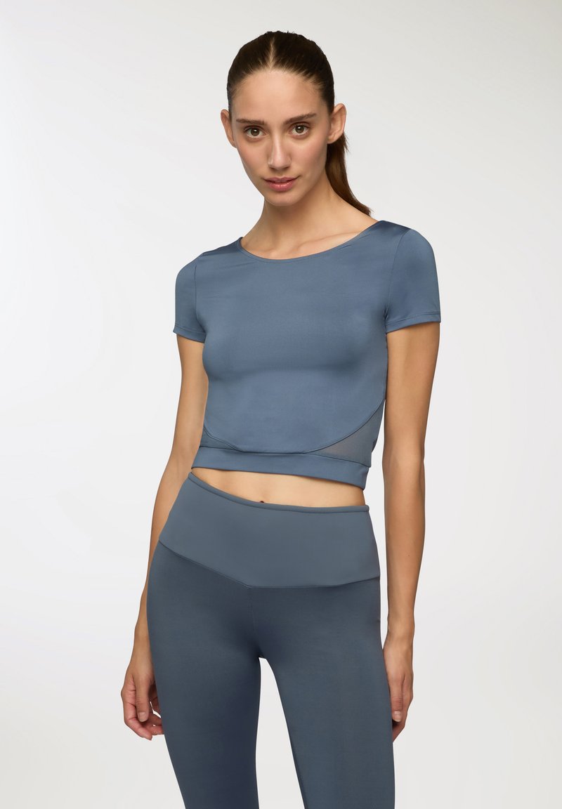 Top corto atletico blu con maniche corte, design senza cuciture e dettagli testurizzati, abbinato a leggings high-waisted coordinati.