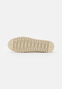 Suela de zapato en color beige con una superficie texturizada, que presenta ranuras horizontales y detalles en relieve. Talla 42 marcada en la zona del talón.