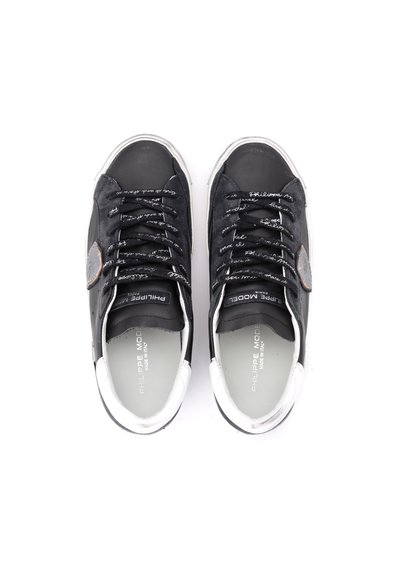 Baskets en cuir noir avec des accents blancs, comportant des lacets, un patch texturé gris et un texte imprimé sur les côtés. Design de bout arrondi et lisse.
