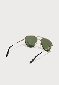 Occhiali da sole aviator in metallo dorato con lenti verde scuro, punte delle fermagliere nere e design a doppio ponte. Stile leggero e minimalista.