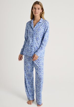 Completo pigiama blu con motivi, composto da maniche lunghe e pantaloni, realizzato in un tessuto morbido che presenta intricati disegni geometrici in diverse sfumature di blu.