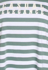 T-shirt rayé en coton vert et blanc, avec le texte "ÉLÉGANCE DÉCONTRACTÉE" en crème. Texture douce, coupe décontractée, larges rayures.