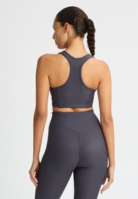 Donkergrijze geribde sportbeha met een racerback-ontwerp, gecombineerd met hoog getailleerde leggings met een naadloze tailleband en een gestructureerde stof.