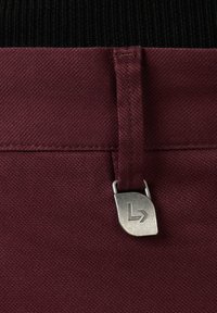 Bordowa tkanina o gładkiej fakturze z metalowym zapięciem w kolorze srebrnym z logo, umiejscowionym w talii.