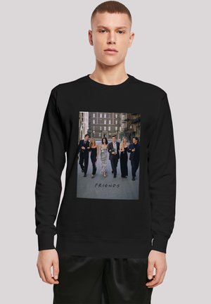 Juoda megztinys su priekinė grafika, vaizduojančia šešis žmones, einančius, su užrašu "F.R.I.E.N.D.S", prieš miesto fono.