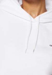 Biała bluza z kapturem z sznurkami, z małym logo na klatce piersiowej i miękką, gładką teksturą tkaniny. Klasyczny design z luźnym krojem.