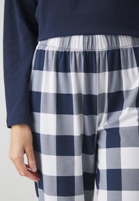 Marinblå långärmad tröja i kombination med vita och marinblå rutig pyjamasbyxor med elastisk midja och mjuk tyggkvalitet.