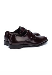 Chaussures habillées en cuir bordeaux avec une finition lisse, orteils arrondis et semelles noires fines. Dotées de lacets et de détails de couture subtils.