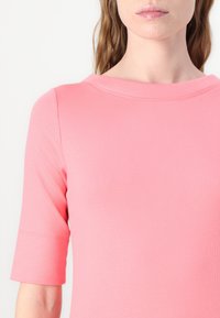Felroze top met korte mouwen en een ronde halslijn, gemaakt van ribbelstof, met een gladde textuur en subtiele naden.