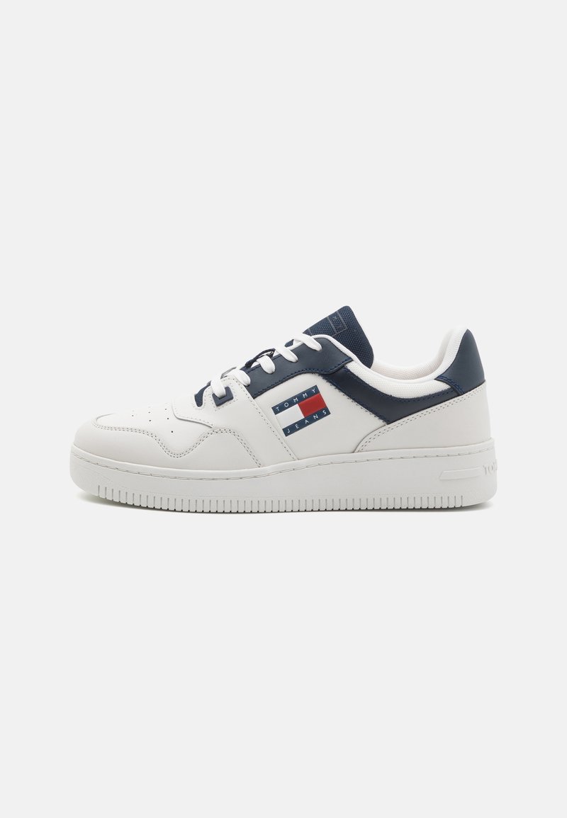 Baskets basses blanches et bleu marine avec fermeture à lacets et logo Tommy Jeans sur le côté, vues de l'extérieur.