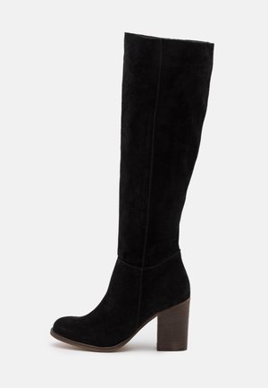 Botte noire en daim, arrivant jusqu'au genou, avec un bout arrondi et un talon en bois épais. Texture lisse avec des détails de couture minimalistes.