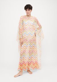 Kaftan multicolor cu model zigzag în nuanțe pastel, realizat dintr-un material ușor; are un guler rotund și mâneci fluide.
