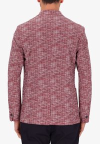 Blazer a vissuto rosso e bianco a motivo spina di pesce, realizzato in tessuto testurizzato, con colletto a revers e chiusure con bottone a due.