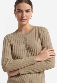 Beżowy kardigan z prążkowanego dzianiny, z okrągłym dekoltem, z zapięciem na guziki i długimi rękawami z teksturowanymi detalami.