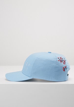 Lyseblå baseballcap med broderede røde blomster på siden og hvid tekst foran, vist på en hvid overflade.