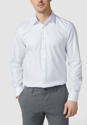 Weißes Langarm-Hemd mit Knopfleiste und klassischem Kragen, das eine glatte Textur aufweist. Kombiniert mit strukturierten grauen Hosen, die einen formellen Look kreieren.