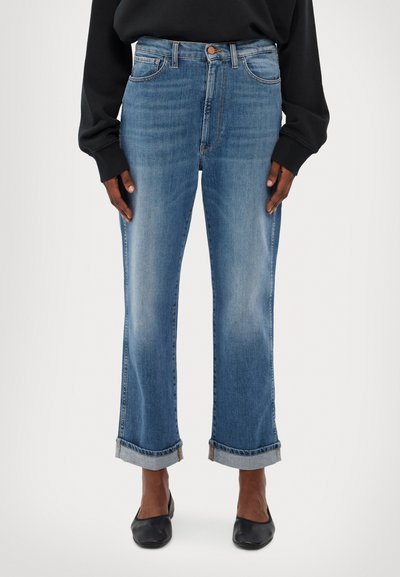 Lyseblå, rette jeans med høy midje, oppbrettede hem, fem lommers design og subtil fading. Kombinert med svarte flate sko.