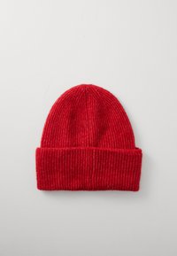 Punane ribakudumine beanie, volditud servaga, valmistatud pehmest villamaterjalist, millel on vertikaalsed jooned ja ümar ülaosa.