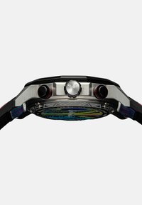 Orologio in acciaio inox con lunetta nera, due pulsanti rossi, quadrante con motivo blu e giallo e cinturino nero testurizzato con dettagli colorati.