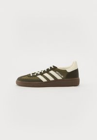 Zielone siatkowe sneakersy z białymi paskami i beżowymi akcentami. Posiadają gumową podeszwę i teksturowaną brązową podeszwę pośrednią. Widoczna nazwa modelu "SPEZIAL".