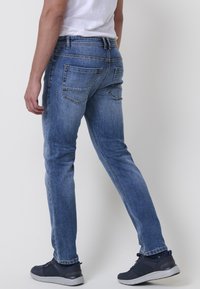 Moške modre denim hlače z oprijetim krojem, z petimi žepi in blagim obrabljenim izgledom. Narejene iz bombaža z gladko teksturo.