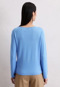 Hellblaues Sweatshirt mit langen Ärmeln, weichem Material, Rundhalsausschnitt und leicht abgerundetem Saum. Trägt man mit beigen Hosen.