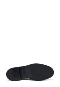 Suela de zapato negra con superficie de goma texturizada, que presenta marcas de la marca, tamaños y un borde liso. Las formas y el diseño enfatizan la funcionalidad.