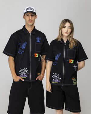 Black short-sleeve shirts with assorted colorful embroidered patches; features a zipper, two pockets, and dark shorts.
