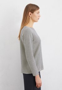 Striped long-sleeve top in black and white, featuring a round neckline and a straight fit, made of soft, textured fabric.