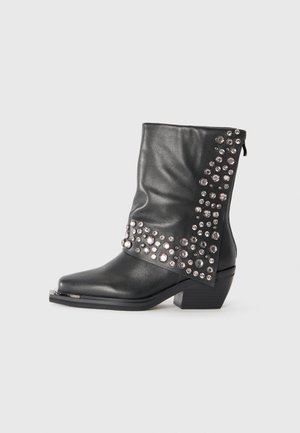 Black mid-calf leather boot with metallic studs arranged in clusters, a pointed toe, block heel, and side zipper closure.