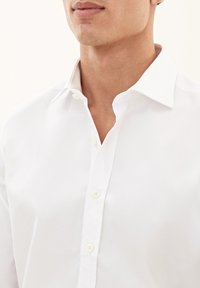 Witte button-down overhemd, gemaakt van katoen, met een klassieke kraag, zichtbare knopen en een gladde textuur. Ontworpen voor een moderne pasvorm.