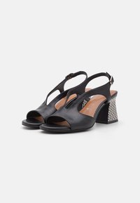 Sorte skinn slingback sandaler med åpen tå, med et mønstret blokkhel og justerbar spenne. Jevn tekstur, moderne design.